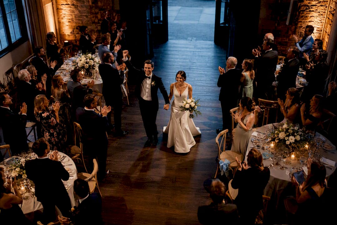Newlyweds entering reception to cheering guests
