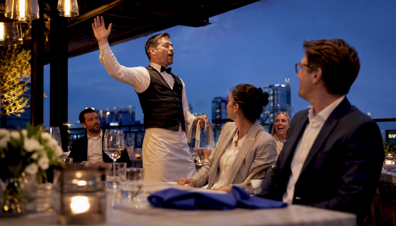 Singing waiter surprising corporate team