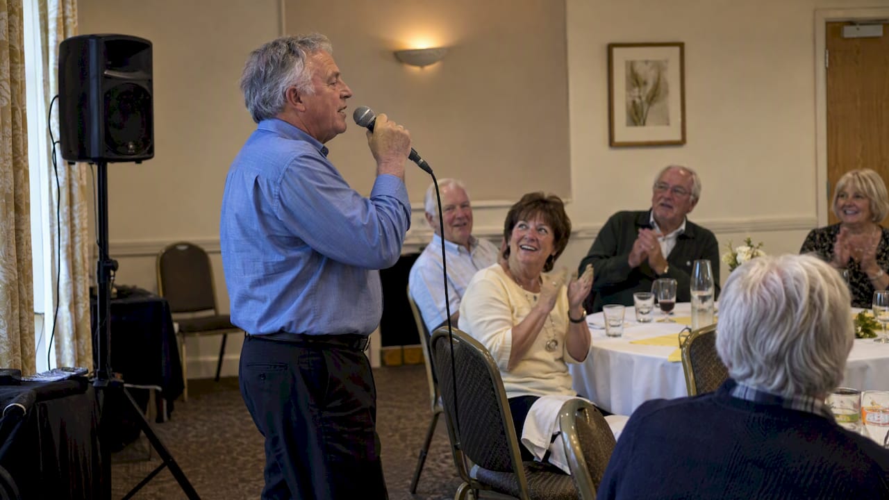 Retirement party guest singing karaoke to colleagues